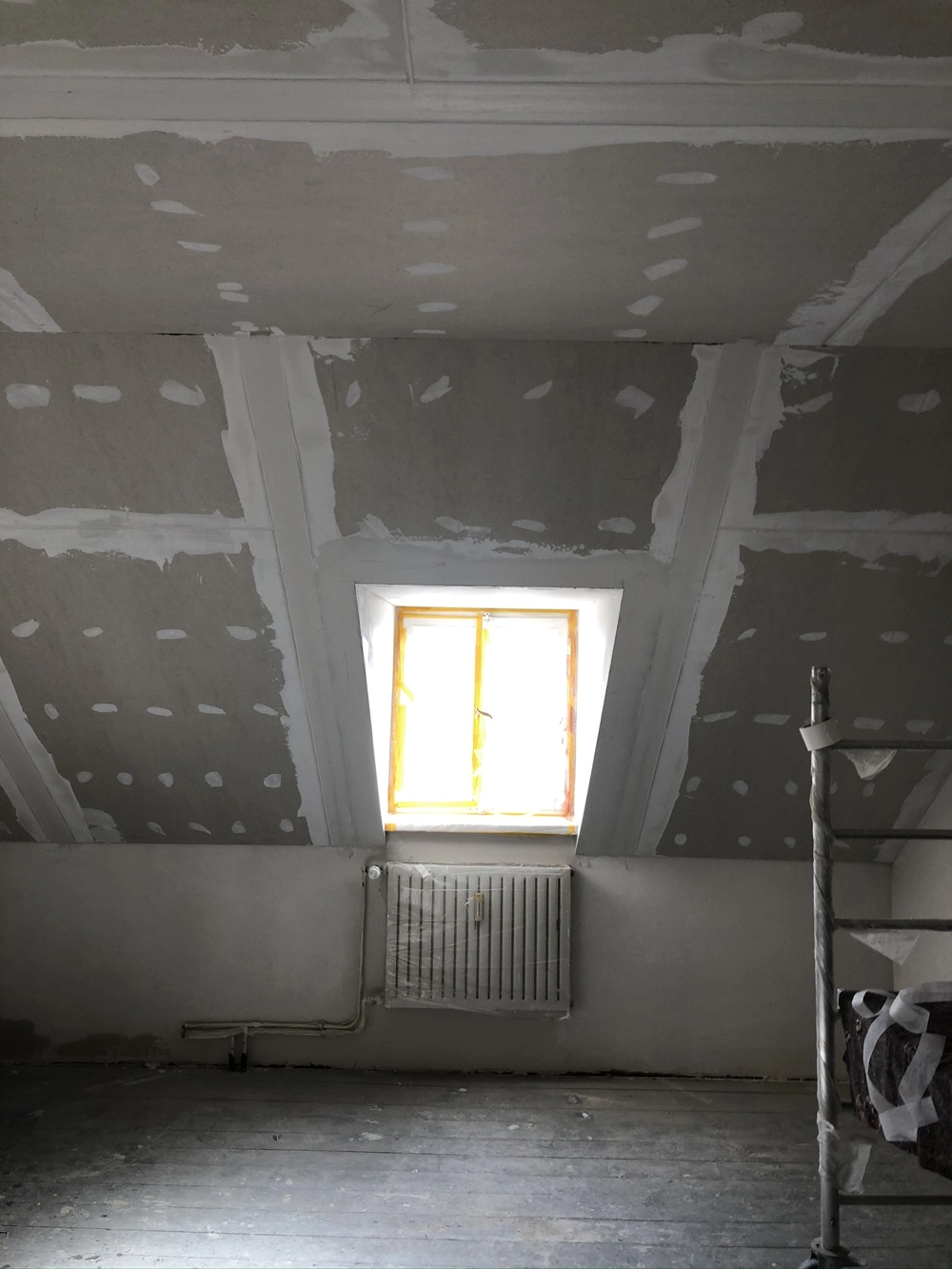 Ausgebauter Dachschrägenbereich mit gespachteltem Trockenbau und neuem Dachfenster