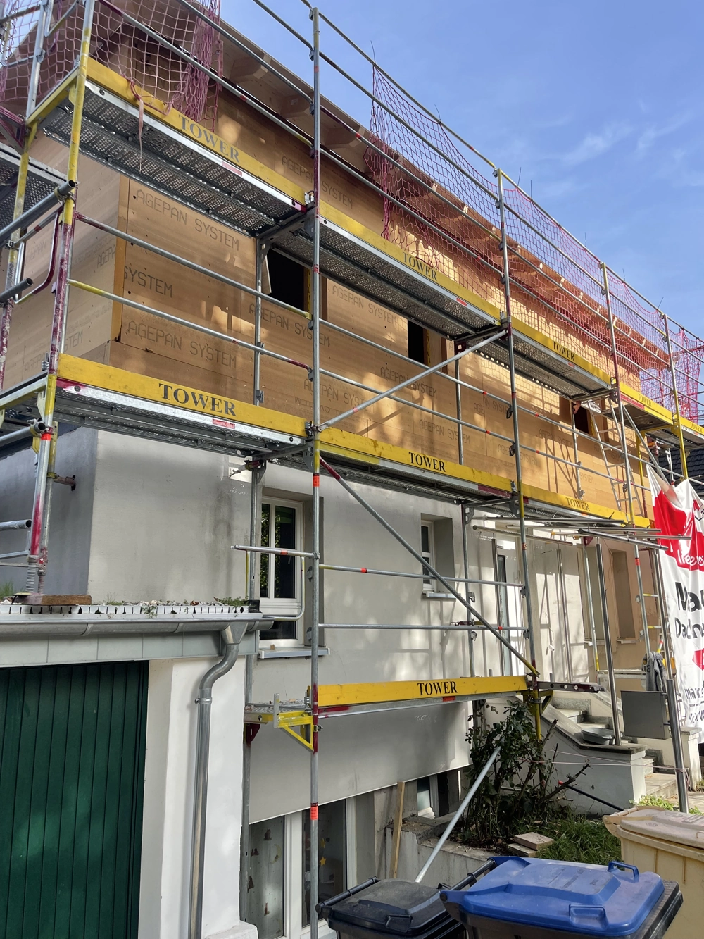 Gerüst vor einem Wohnhaus mit aufgebrachter Fassadendämmung und vorbereiteten Fensteröffnungen