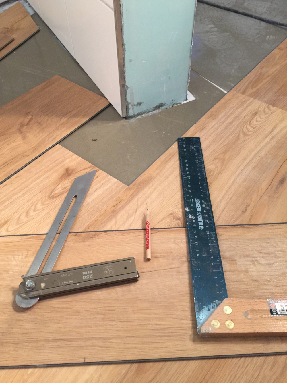 Laminat verlegen um eine Stützsäule mit Winkel, Falzlehre und Bleistift
