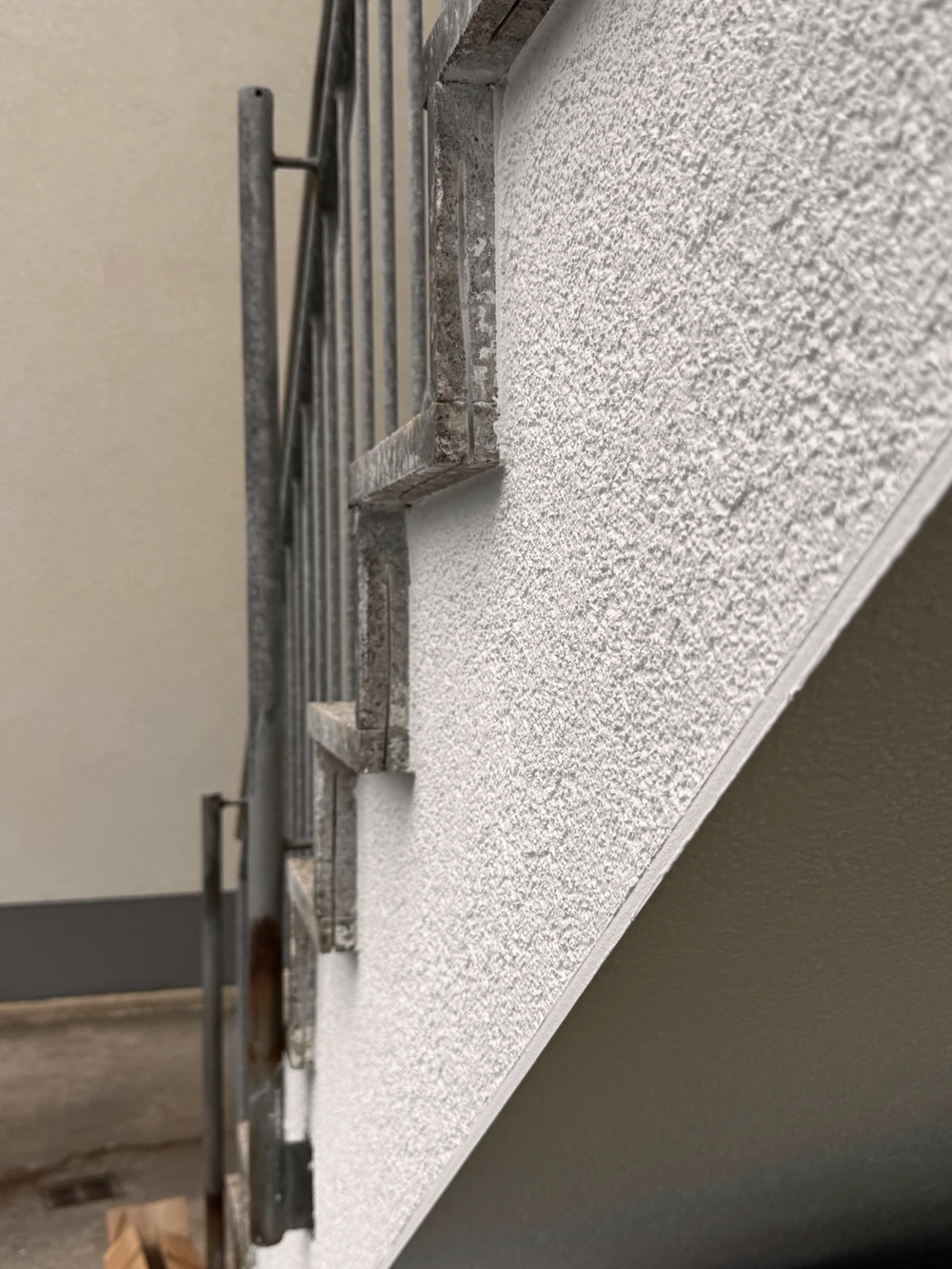 Tynkowanie fragmentu elewacji przy schodach z metalową balustradą
